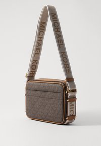 Borsa a tracolla marrone con motivo, dotata di hardware dorato e ampia tracolla in tessuto con il testo "MICHAEL KORS". Bordo in pelle liscia lungo i lati.