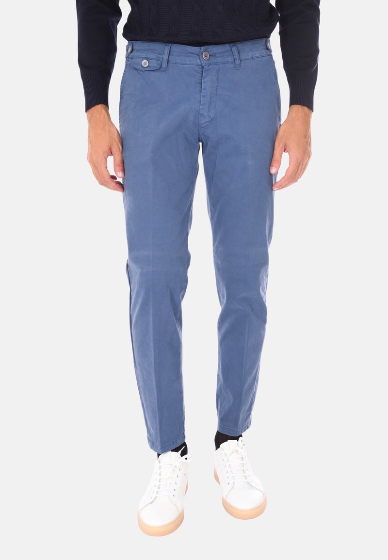 Chinos blu in cotone con un design slim fit, caratterizzati da tasche frontali e chiusura a un pulsante. Abbinati a sneakers bianche.