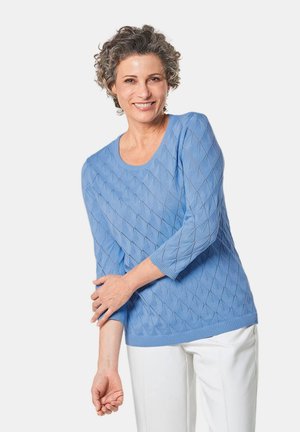 Maglione blu chiaro con motivo a rombi, colletto e polsini a coste, maniche tre quarti, abbinato a pantaloni bianchi. Tessuto a maglia testurizzato.