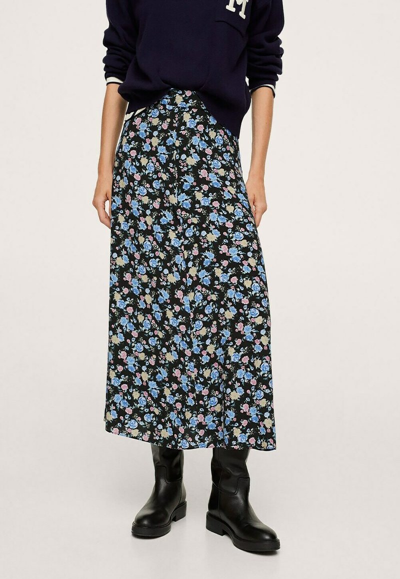 Gonna maxi floreale in tessuto nero, con fiori blu, rosa e beige, dal taglio rilassato e dettagli con spacco laterale, abbinata a stivali neri alla caviglia.