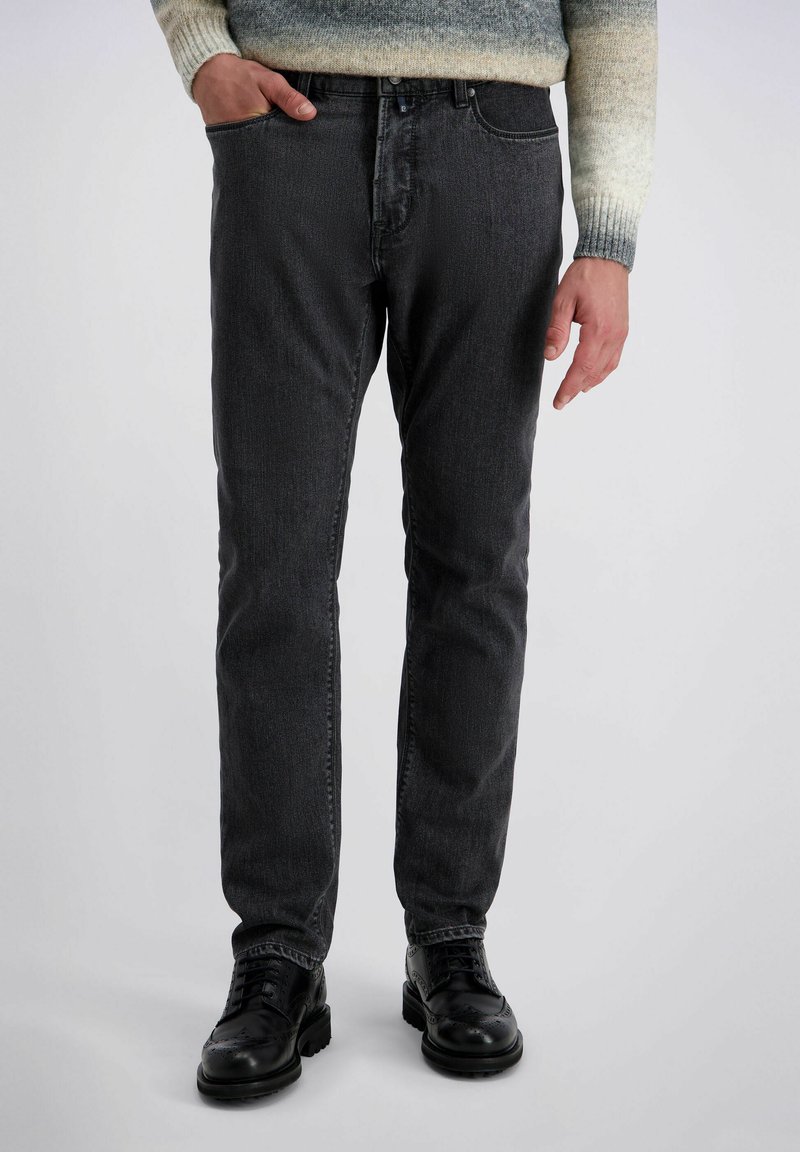 Donkergrijze denimjeans met een rechte fit, voorzien van een knoopsluiting, steekzakken en een subtiele textuur. Gecombineerd met zwarte leren schoenen.