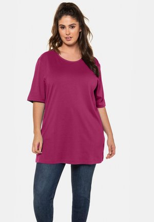 Magenta-T-Shirt aus weichem Material, mit rundem Halsausschnitt und kurzen Ärmeln, kombiniert mit dunkelblauen Skinny-Jeans. Einfaches Design.