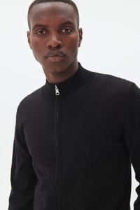 Black zip-up sweater with a ribbed collar, made from a textured fabric. Features a silver zipper and fitted silhouette.
