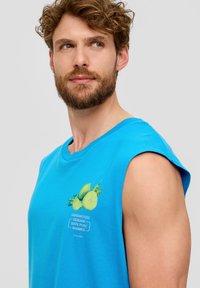 Blauw mouwloos T-shirt van een zachte katoenmix, met een fruitafbeelding en tekst op de voorkant. Soepele textuur en een relaxte pasvorm.