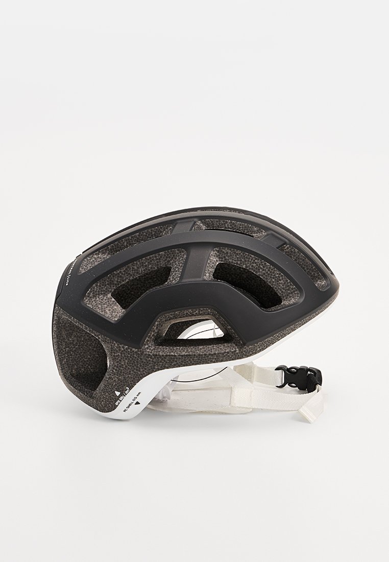 Casco da ciclismo nero e texture, con ampie aperture di ventilazione, un lato inferiore bianco liscio e una fibbia regolabile per il mento.