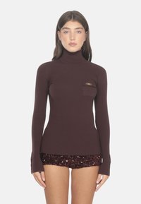 Brauner, gerippter Rollkragenpullover mit taillierter Passform. Verfügt über eine kleine Brusttasche und lange Ärmel mit dezentem Ausstellen an den Bündchen.