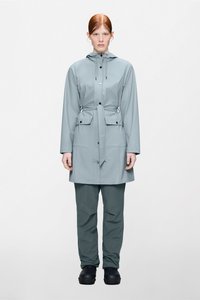 Ανοιχτό γκρι αδιάβροχο παλτό με κουκούλα, κουμπιά μπροστά και κορδόνι στη μέση, σε συνδυασμό με σκούρο πράσινο αδιάβροχο παντελόνι και μαύρα υποδήματα.