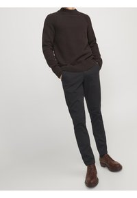 Mörkbrun stickad tröja med ribbade manschetter och nederkant, matchad med slim-fit svarta byxor och bruna läderskor med snörning och strukturerad sula.
