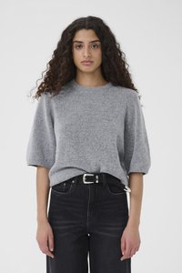 Maglione grigio lavorato a maglia con maniche corte, caratterizzato da uno scollo rotondo e una consistenza morbida, abbinato a jeans neri a vita alta e cintura argentata.
