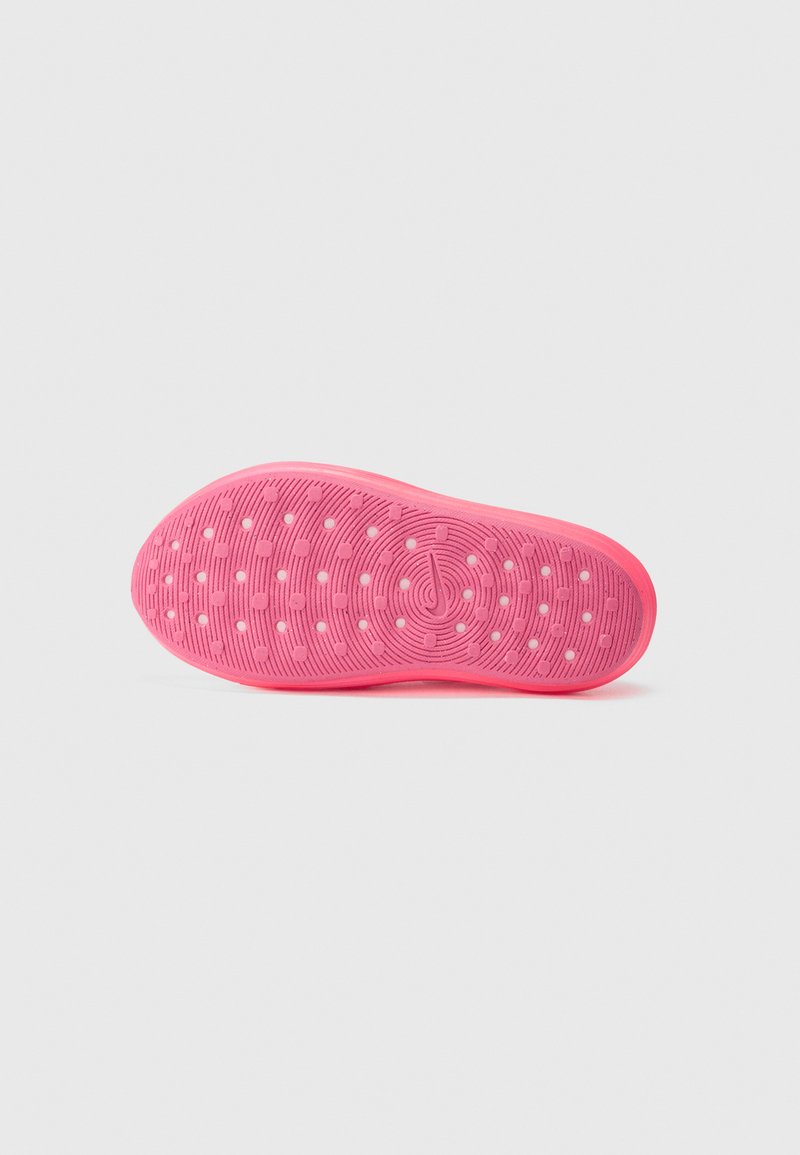 Suela de zapato de goma rosa con una superficie texturizada que presenta patrones circulares y orificios de ventilación para tracción y transpirabilidad.