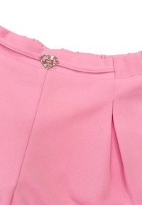 Blusa rosa con una texture liscia, dotata di una piccola chiusura a forma di cuore argentato sul retro e dettagli di leggero plissè.