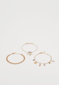 Three gold bracelets: a chunky chain, a delicate chain with charms, and another with small pendants and a central stone.