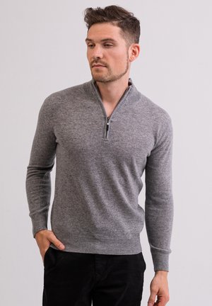 Sudadera gris con cremallera hecha de un tejido texturizado, que presenta puños y dobladillo acanalados, y una cremallera media en el cuello para un ajuste ajustable.