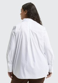 Wit overhemd met knopen, voorzien van kleine, subtiele stippen, lange mouwen en een plooi aan de achterkant voor meer bewegingsvrijheid. Glad stof en een klassieke kraag.