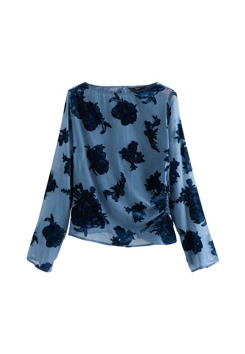 Haut à manches longues bleu en tissu transparent avec des motifs floraux bleu marine. Il présente un col rond et un détail froncé sur le côté.