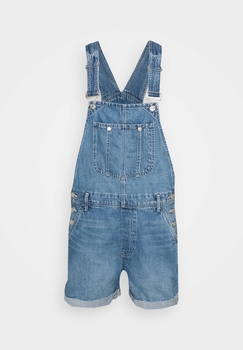 Salopette courte en jean bleu avec bretelles réglables, poche avant sur le plastron, boutons latéraux et ourlets roulés sur le short.