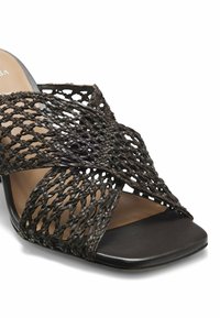 Sandale noire à orteils ouverts avec des brides croisées en cuir tressé et une semelle de forme carrée.