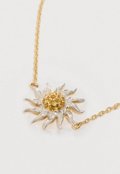 Zlatý řetízek s přívěskem ve tvaru slunce se středovým kulatým žlutým drahokamem a stříbrnými akcenty, z nichž vyzařují texturované paprsky.
