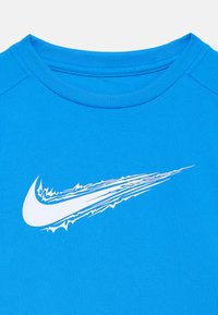 Camiseta deportiva azul con cuello redondo, mangas cortas y una textura en la tela que presenta un logo dinámico de Nike en blanco en la parte frontal.