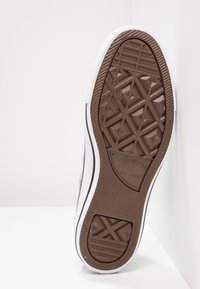 Brown rubber sneaker sole with a diamond tread pattern, white sidewall, and branding. Smooth texture and low-profile design.