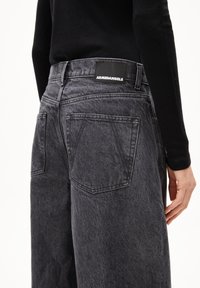 Schwarze Jeans mit leicht ausgewaschener Textur, mit Gesäßtaschen und einem ARMEDANGELS Logo-Patch am Bund.