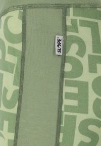 Green athletic top featuring a ribbed texture and bold repeating graphic pattern. A small label with "SLOPE" is sewn on the side seam.