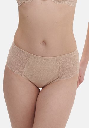 Vrouw die beige kanten slips met een middenhoge taille en een bijpassende beha draagt, tegen een effen witte achtergrond.