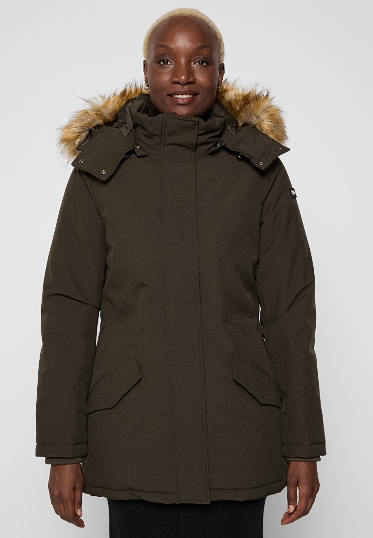 Parka marron avec une capuche doublée de fausse fourrure, fermeture éclair à l'avant et deux poches latérales. Étoffe douce et texturée.
