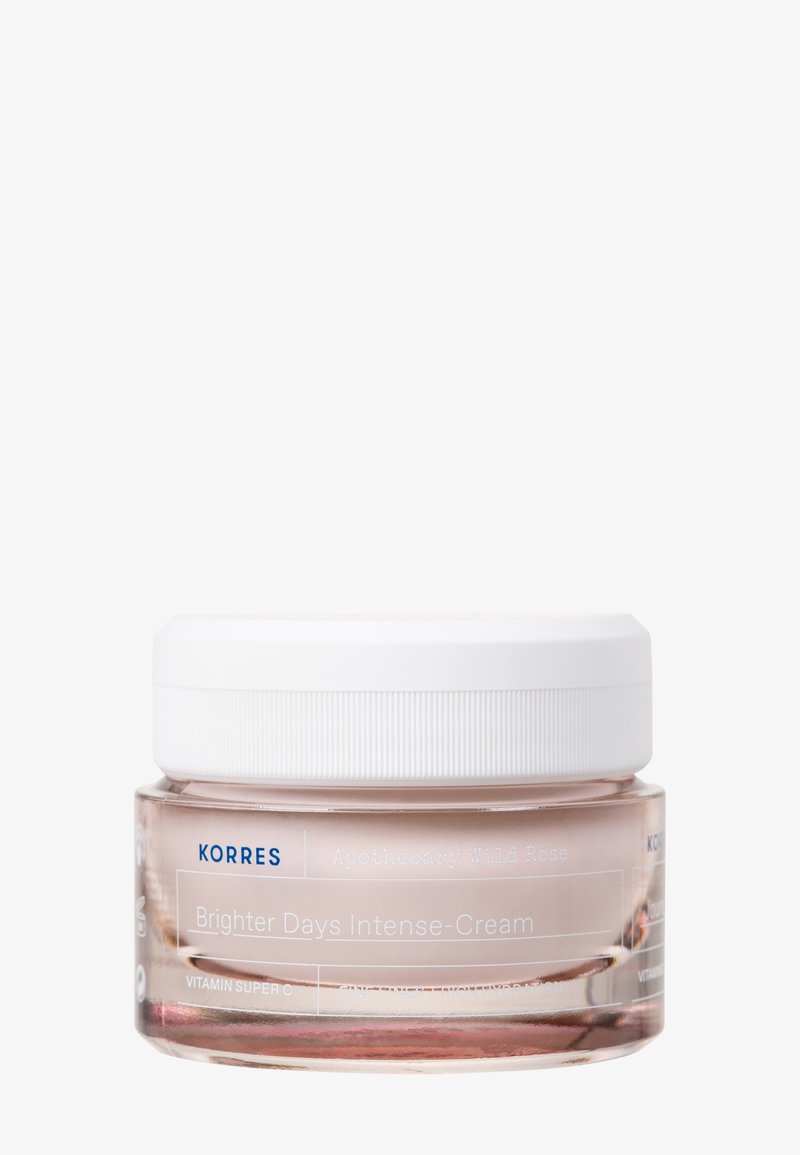 Crème Intense Korres Brighter Days dans un pot en verre transparent avec une teinte rose et un couvercle blanc ; étiquetée avec des détails du produit en texte bleu.
