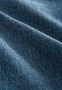 Tessuto di denim blu scuro con una consistenza liscia, caratterizzato da motivi diagonali a spina di pesce e sottili variazioni di colore, che creano profondità e interesse.