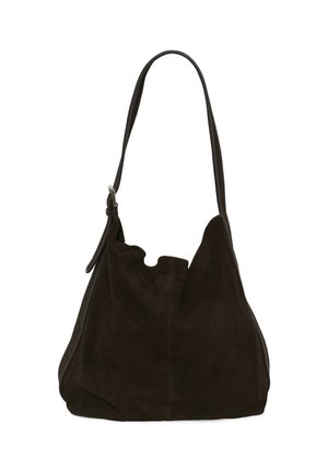 Femme portant un blazer à carreaux gris, un haut à manches longues foncé, un pantalon large noir, tenant un grand sac en daim marron avec une bandoulière.