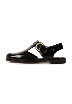 Black patent leather closed-toe sandal with a gold buckle strap and cut-out sides, flat sole, and open heel.