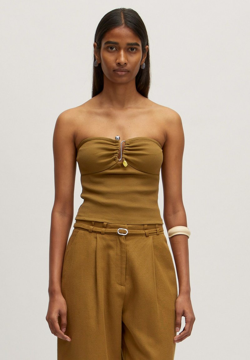 Braunes, geripptes, schulterfreies Oberteil mit einem gerafften Zentrum und metallic Detail. Kombiniert mit hoch taillierten, weiten Hose im gleichen Stil.