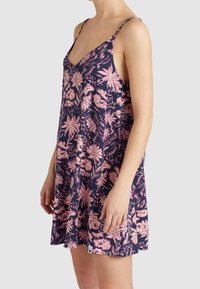 Kukkamekko, jossa on syvä V-pääntie, ohuet hihnat ja levenevä helma. Taustana tummansininen väri vaaleanpunaisilla kukkakuvioilla ja sivutagi.