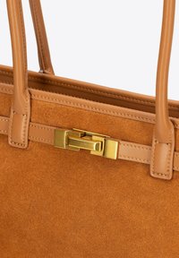 Torebka w kolorze tan, wykonana z miękkiego zamszu, z skórzanymi uchwytami. Posiada złoty prostokątny zamek oraz detale w postaci szwów wzdłuż brzegów.