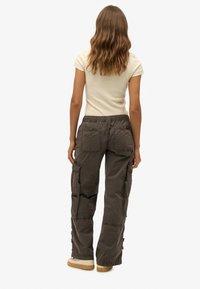 Cargo-Hosen in dunkelolivgrün, mit lockerer Passform, elastischem Bund und mehreren Taschen. Der Stoff hat eine strukturierte Oberfläche.