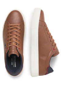 Brown leather sneakers with white rubber sole, flat laces, and navy accents. Features logo detailing and a textured finish on the upper.