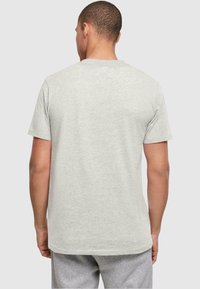 Camiseta de manga corta gris hecha de tejido suave, con un escote redondo y un corte relajado, mostrada desde la parte de atrás.