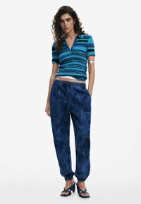 Short-sleeve, blue striped knit top paired with dark blue, loose-fitting jogger pants featuring elastic cuffs and pockets.
