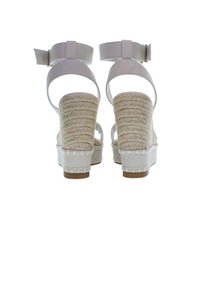 Bílé espadrilky na platformě s tkanou jute texturou na podpatku, nastavitelným řemínkem kolem kotníku a hladkým textilním svrchním materiálem, se silnou podešví.