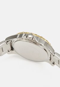 Sølv rustfrit stål ur med en guldfarvet bezel, tekstureret krone og metal link armbånd; har en enkel bagside.
