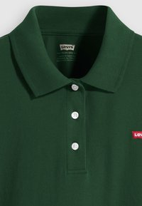 Donkergroen polo-shirt gemaakt van textiel met structuur, voorzien van een kraag, drie witte knopen en een klein rood Levi's-logo op de linkerborst.