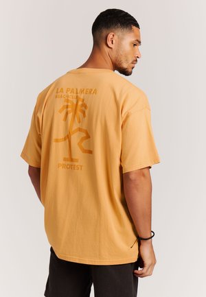 Oranje katoenen t-shirt met korte mouwen, voorzien van een grafisch ontwerp van een palmboom en de tekst "LA PALMERA BEACHCLUB PROTEST" op de achterkant.