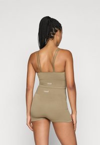 Ελαιόχρωμο σπορ σύνολο με εφαρμοστό crop top και σορτς ψηλής μέσης. Διαθέτει λεπτές τιράντες και υφαντό ύφασμα με ορατή σήμανση.