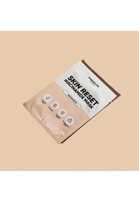 Verpackung der Niacinamid-Maske in hellbeige mit weißem und schwarzem Text. Enthält Symbole für Hautvorteile und Recycling. Mattes Finish.