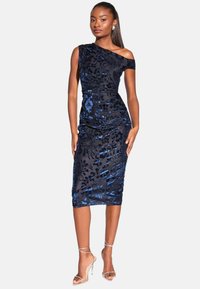 Asimetrisks melns kleita ar ziliem ziedu rakstiem. Tievs piegriezums, līdz ceļgaliem, savilktas tekstūras, kopā ar caurspīdīgām siksnām ar papēžiem.