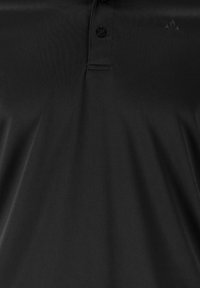 Polo noir avec patte de boutonnage à deux boutons et petit logo brodé sur la partie supérieure gauche de la poitrine.