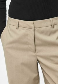 Bēšas bikses ar gludu tekstūru, uzlabotā piegriezumā, ar jostas cilpām un sānu kabatām. Kombinētas ar melnu ribotu augšdaļu.