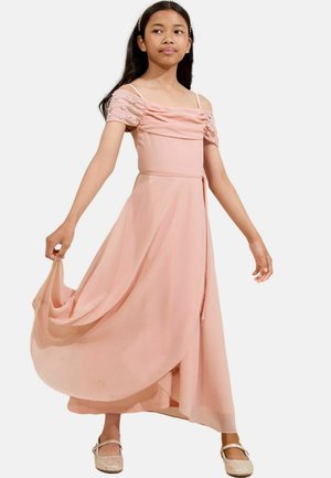 Abito rosa con un corpetto aderente e maniche a sbuffo arricciate adornate con perline. La gonna fluida e leggera esalta il movimento. Indossato con scarpe basse.