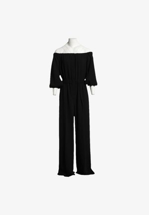 Mono negro con escote barco, mangas abullonadas tres cuartos y perneras anchas, exhibido en un maniquí sin cabeza.